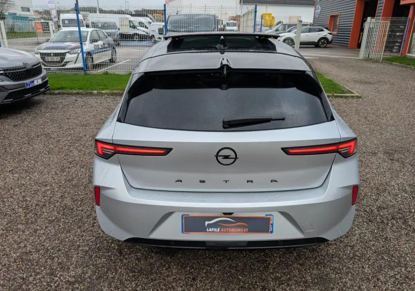 Vue arrière d'une Opel Astra gris métallisé avec feux LED fins et vitres arrière surteintées.