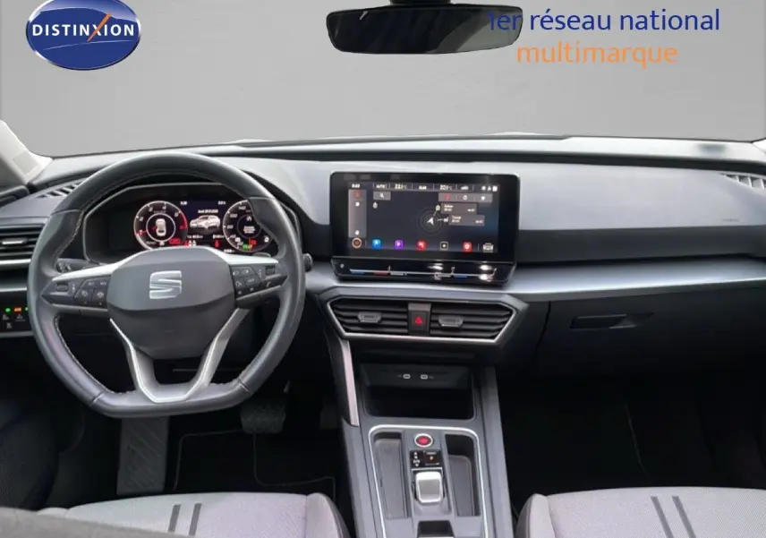 Vue intérieure du tableau de bord et volant du SEAT LEON ST gris urbain, avec écran tactile central et commandes modernes.