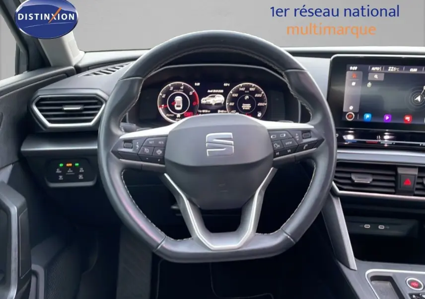 Intérieur du SEAT LEON ST 2022, vue centrée sur le volant cuir et tableau de bord numérique avec écran tactile.