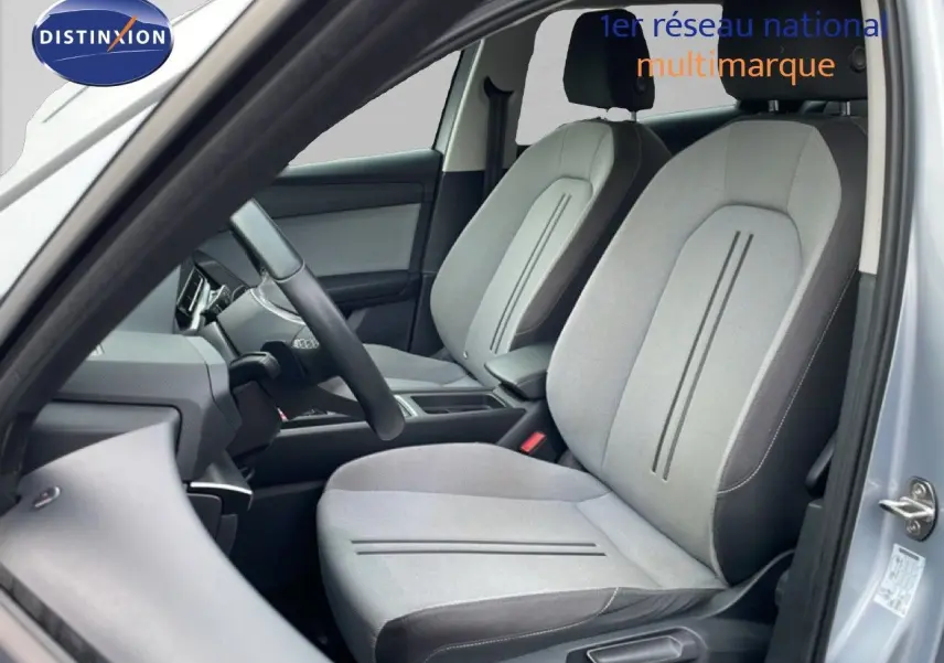 Vue intérieure côté conducteur du SEAT LEON ST 2022, sièges tissu gris clair avec détails sombres, ambiance épurée.