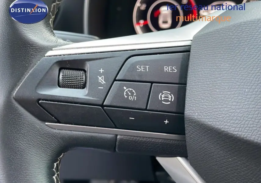 Gros plan sur les commandes de régulateur de vitesse au volant de la SEAT LEON ST 2.0 TDI 2022, intérieur noir.