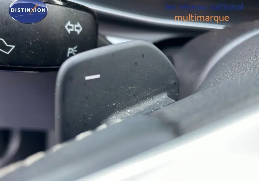 Gros plan sur la palette de changement de vitesse au volant d’une SEAT LEON ST gris urbain métal, intérieur noir.