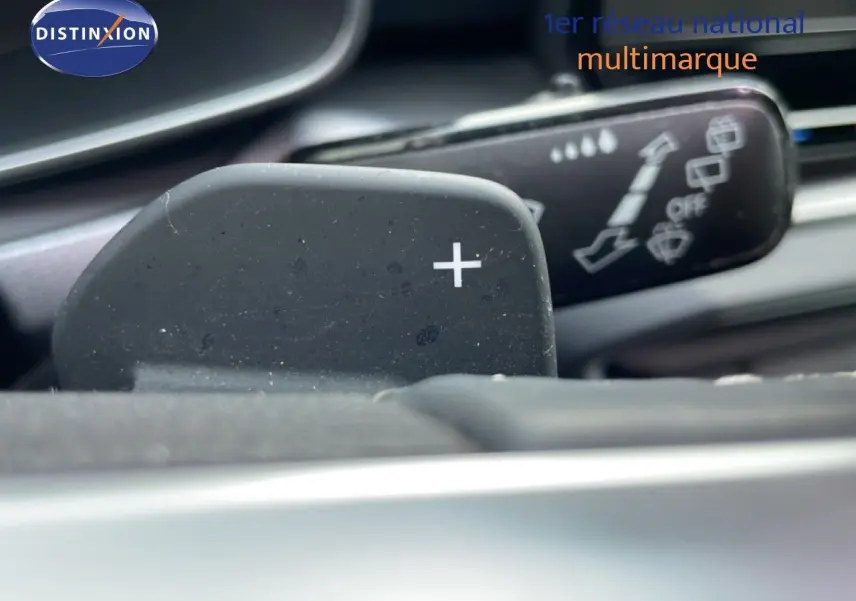 Gros plan sur la palette de changement de vitesse "+" côté droit dans l'habitacle d'une SEAT LEON ST gris urbain.