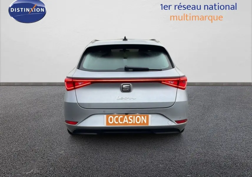 Vue arrière d'une SEAT Leon ST 2022 gris urbain métal avec feu arrière continu et plaque d'immatriculation "OCCASION".