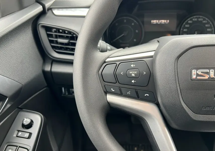 Gros plan sur le volant multifonctions gris foncé et la partie gauche du tableau de bord noir de l'Isuzu D-MAX.