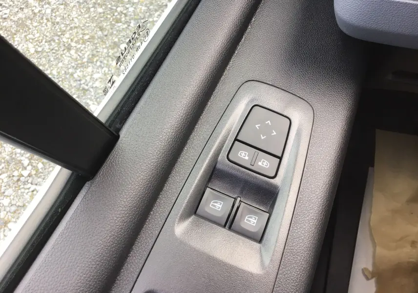 Gros plan sur les commandes électriques des vitres et rétroviseurs côté conducteur du Renault Master blanc, intérieur noir.