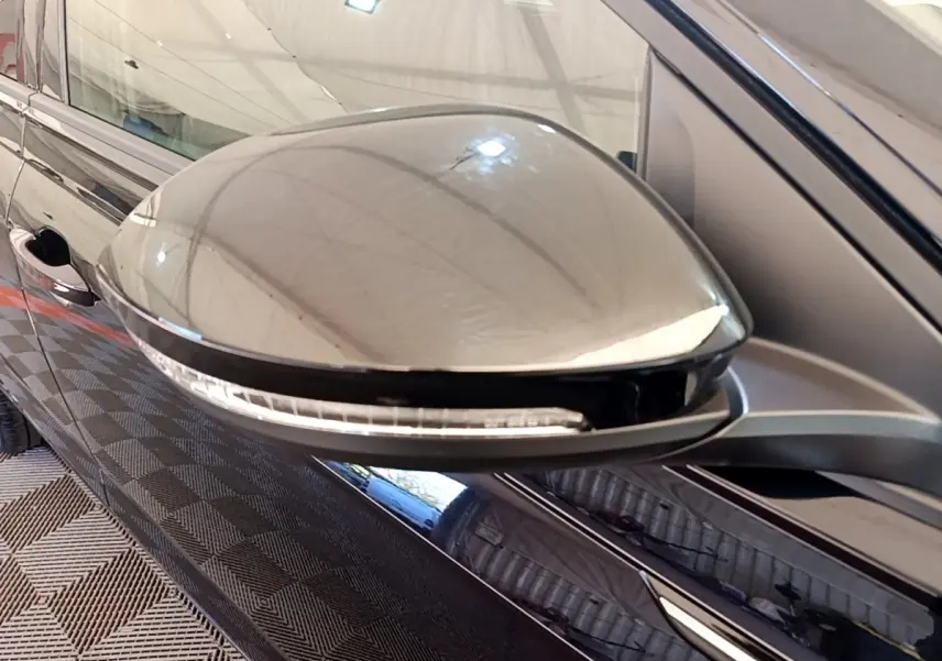 Gros plan sur le rétroviseur côté gauche noir brillant du Volkswagen Taigo 1.5 TSI 150 DSG R-Line 2023.