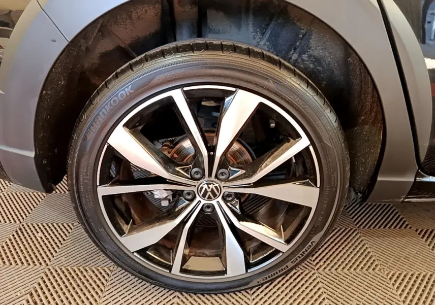 Gros plan sur la roue avant droite noire du Volkswagen Taigo 1.5 TSI 150 DSG R-Line avec jante alliage bicolore.