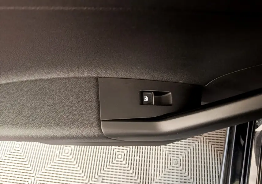 Détail de la commande de verrouillage sur la portière intérieure noire d’un Volkswagen Taigo 1.5 TSI 150 DSG R-Line 2023.