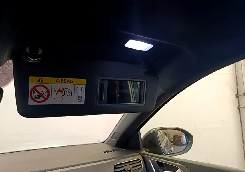 Vue intérieure côté conducteur du Volkswagen Taigo noir 2023, avec pare-soleil ouvert et miroir intégré éclairé.