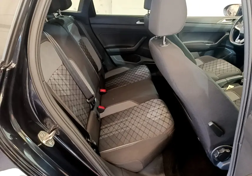 Vue intérieure côté gauche sur la banquette arrière et sièges avant du Volkswagen Taigo noir 2023 avec sellerie tissu à motifs.
