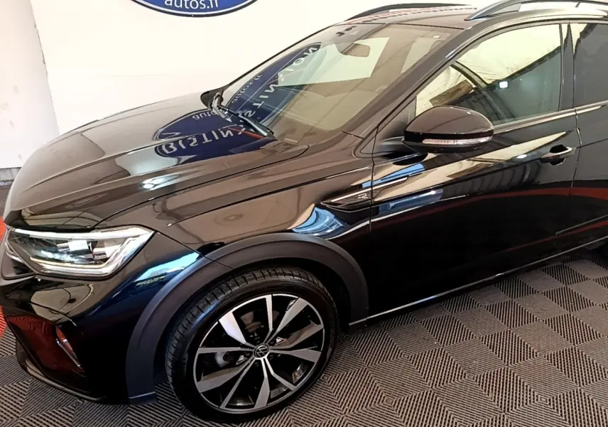 Vue de profil avant droit du Volkswagen Taigo noir 1.5 TSI R-Line avec jantes alliage et rétroviseur noir brillant.