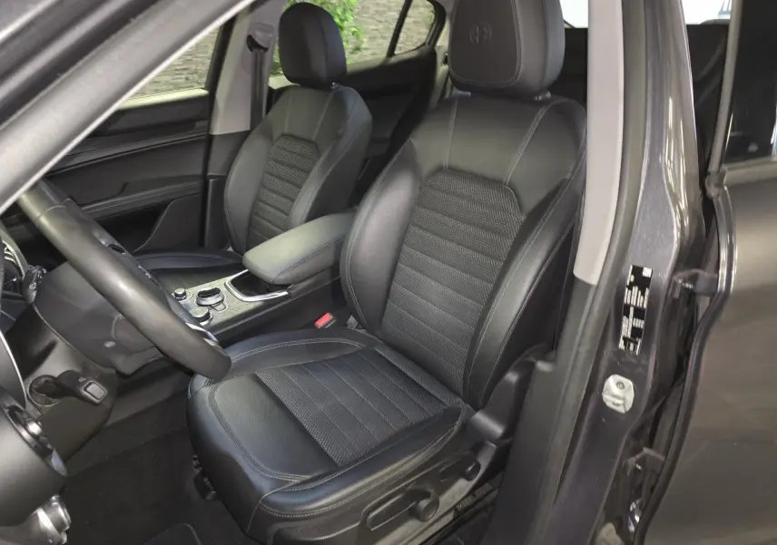 Vue intérieure côté conducteur de l'Alfa Romeo Stelvio gris 2022, sièges tissu noir et volant sport cuir.