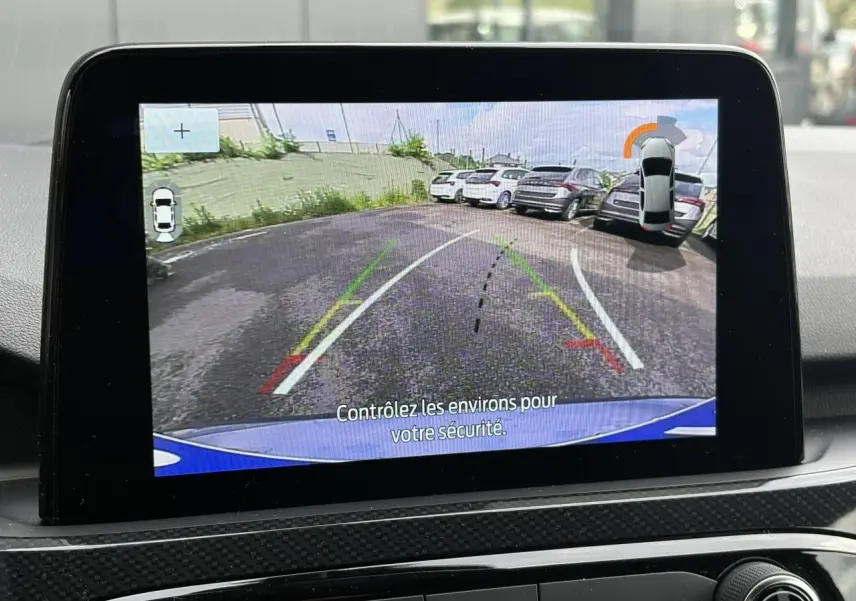 Écran tactile intérieur montrant la caméra de recul du Ford Kuga bleu azur, avec lignes d’aide au stationnement.