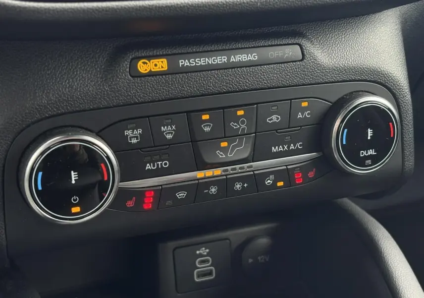 Vue rapprochée du tableau de bord du Ford Kuga 2023, montrant la climatisation automatique bi-zone et commandes chauffantes.