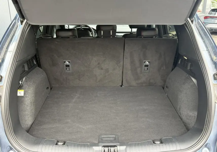 Coffre ouvert vu de l'arrière d'un Ford Kuga bleu azur 2023, banquette arrière en position verticale.
