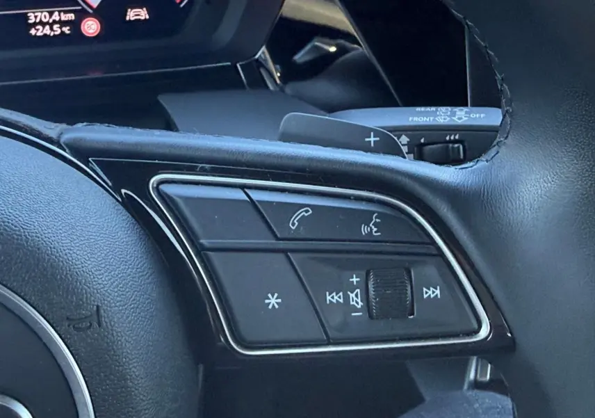 Gros plan sur les commandes vocales et audio au volant cuir noir de l'Audi A3 Sportback 2024.