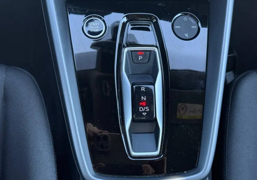 Gros plan sur la console centrale noire brillante avec sélecteur de boîte auto et bouton Start/Stop de l'Audi A3 Sportback 2024.