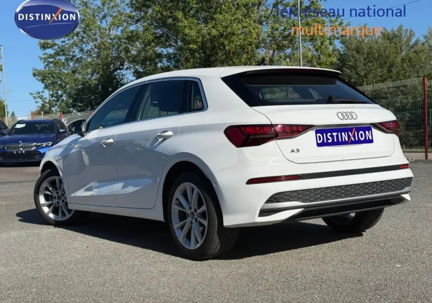 Audi A3 Sportback blanc Arkona vue 3/4 arrière droit, avec jantes alu et becquet noir distinctif.