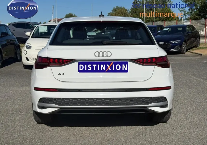 Vue arrière d'une Audi A3 Sportback blanche Arkona 2024 avec feux arrière LED et logo Audi visible.