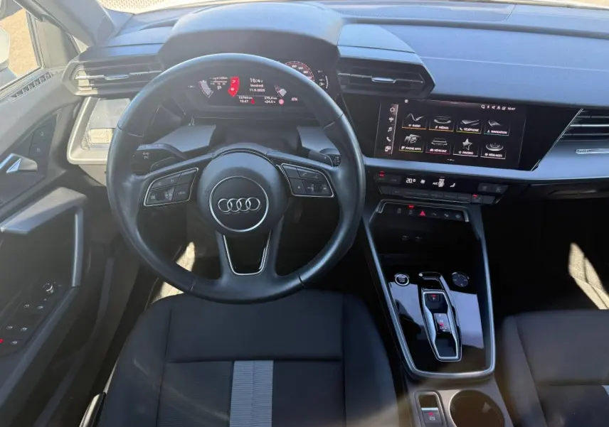 Vue intérieure frontale de l'Audi A3 Sportback 2024, volant cuir noir, écran tactile et console centrale brillante.