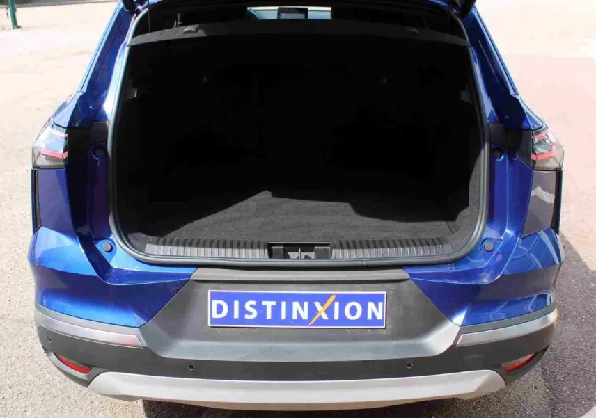 Vue arrière ouverte du coffre d’un Renault Symbioz bleu avec pare-chocs noir et plaque Distinxion.