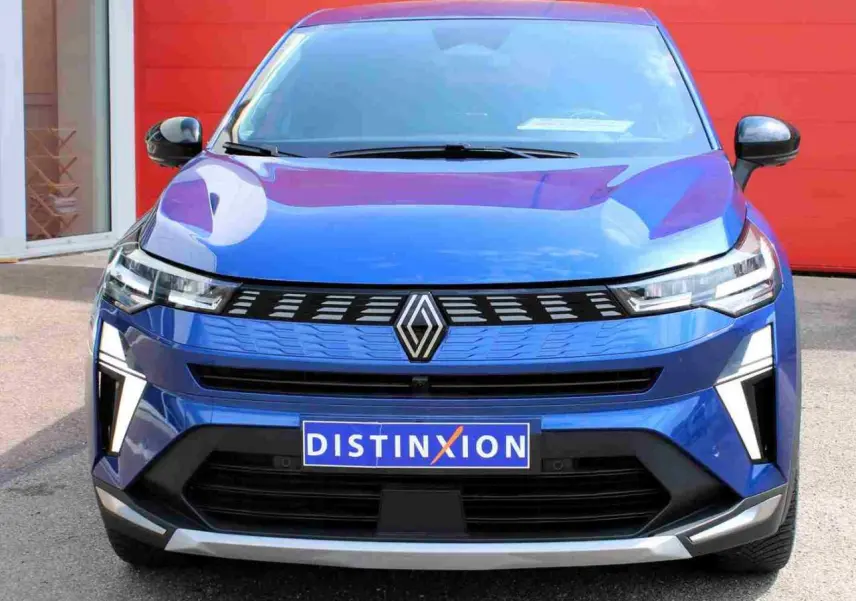 Vue avant d'une Renault Symbioz 2025 bleu Iron avec calandre 3D et feux LED distinctifs sur fond rouge.