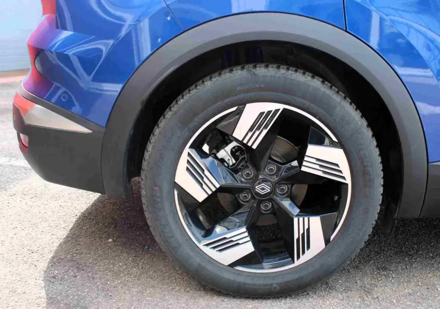 Gros plan sur la roue arrière droite du Renault Symbioz bleu avec jante alliage 19 pouces au design noir et argent.
