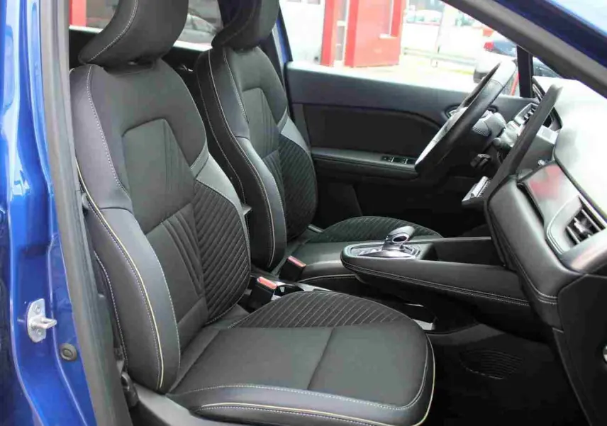 Vue intérieure côté conducteur de la Renault Symbioz 2025 bleu, sièges noirs avec surpiqûres contrastées et console centrale moderne.