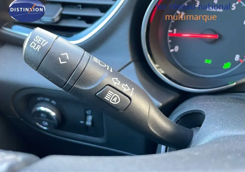 Gros plan sur la manette de clignotant et feux automatiques du tableau de bord d'un Opel Grandland X blanc toit noir.