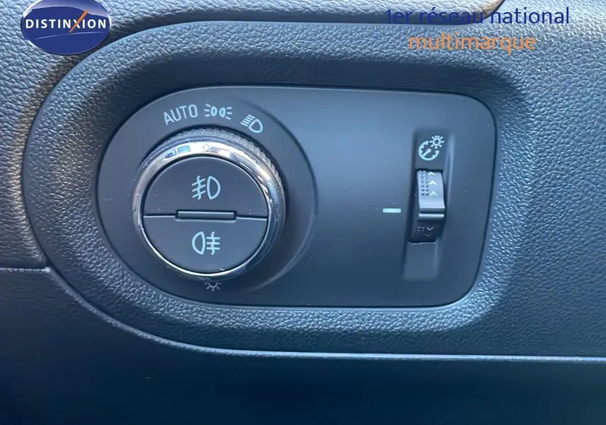 Gros plan sur le bouton de commande des phares dans l'habitacle noir de l'Opel Grandland X blanc toit noir.