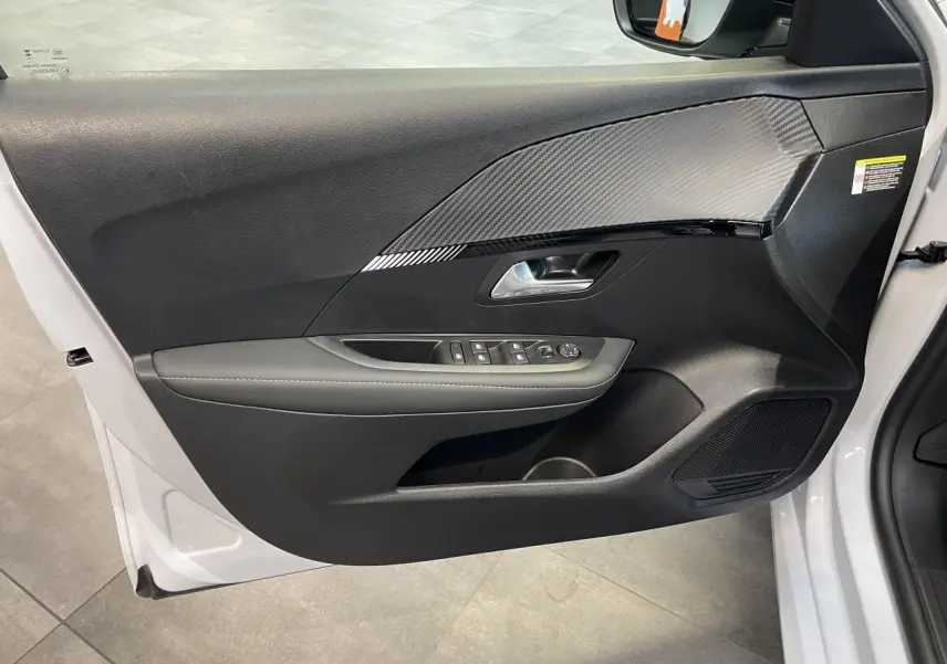 Vue intérieure côté gauche de la porte avant blanche okenite de la Peugeot 208 avec habillage noir et insert effet carbone.
