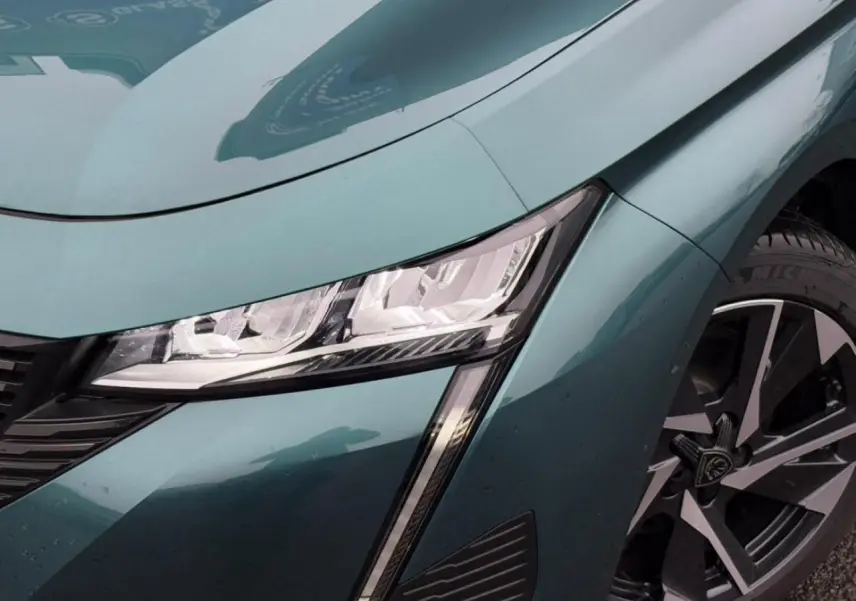 Gros plan sur l'avant droit bleu cuivre du Peugeot 308 SW Hybrid, mettant en valeur le phare LED et la jante alliage.