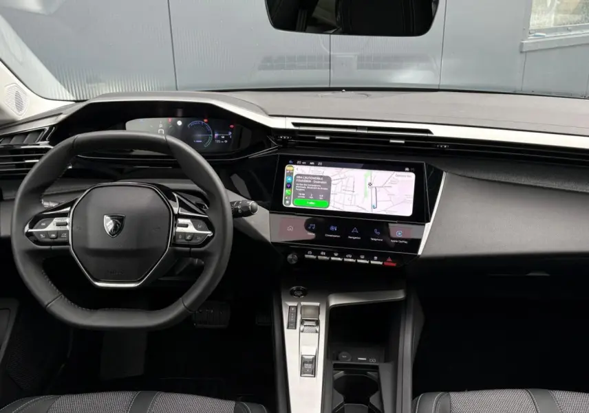 Vue intérieure du poste de conduite de la Peugeot 308 SW Hybrid 145, avec écran tactile et volant compact noir.