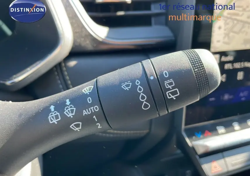 Gros plan sur la manette d’essuie-glace du tableau de bord d’une Renault Symbioz noire, avec commandes visibles.
