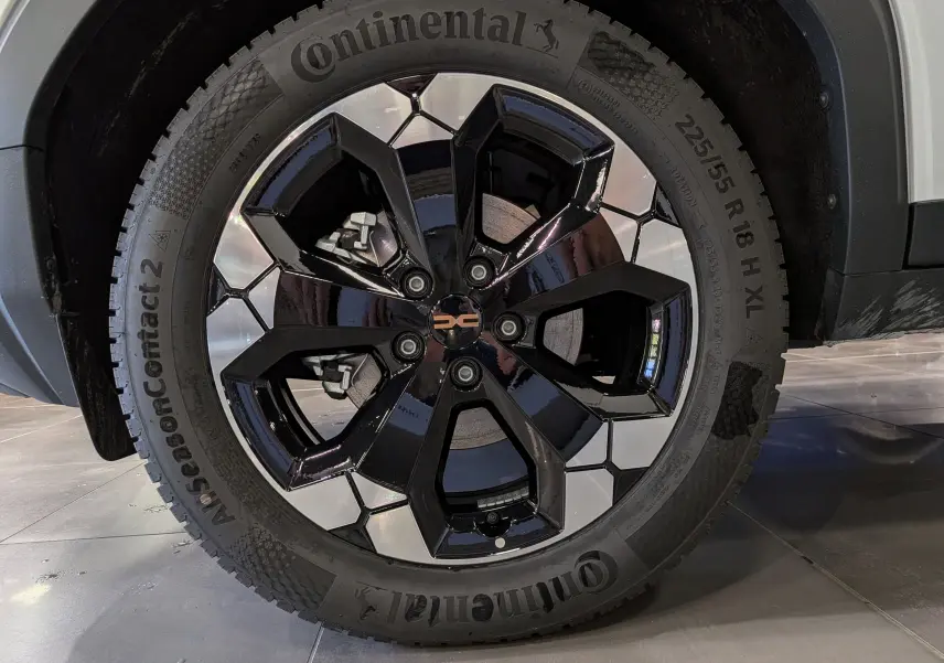 Gros plan sur la roue avant droite du Dacia Bigster blanc Glacier, jante noire et argentée au design hexagonal.