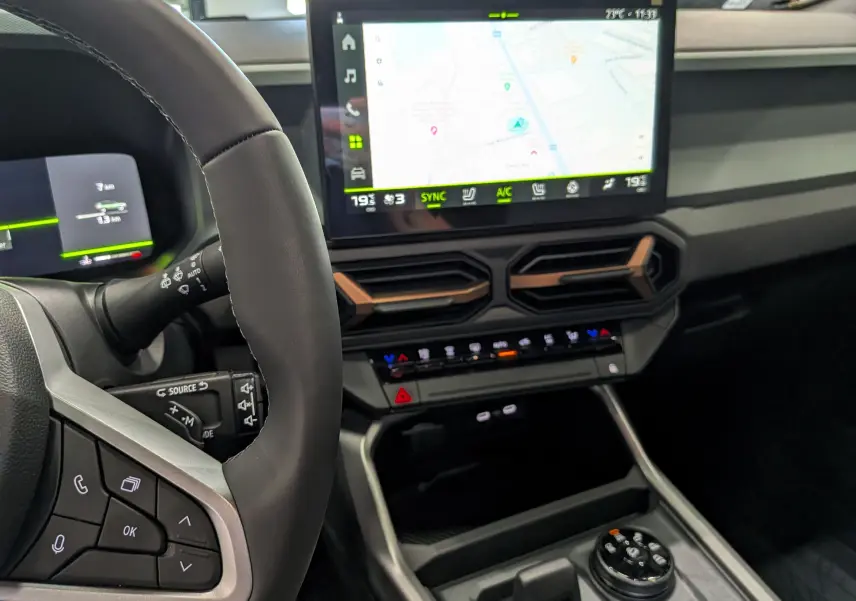 Vue intérieure rapprochée du tableau de bord et volant du Dacia Bigster Hybrid-G 150, avec écran tactile et commandes modernes.