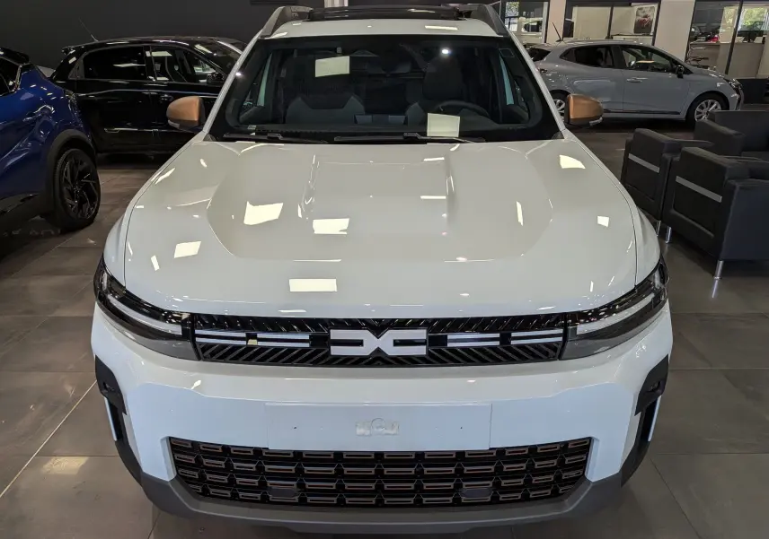 Vue avant du Dacia Bigster Hybrid-G 150 4x4 en blanc glacier, avec calandre noire et logo central distinctif.