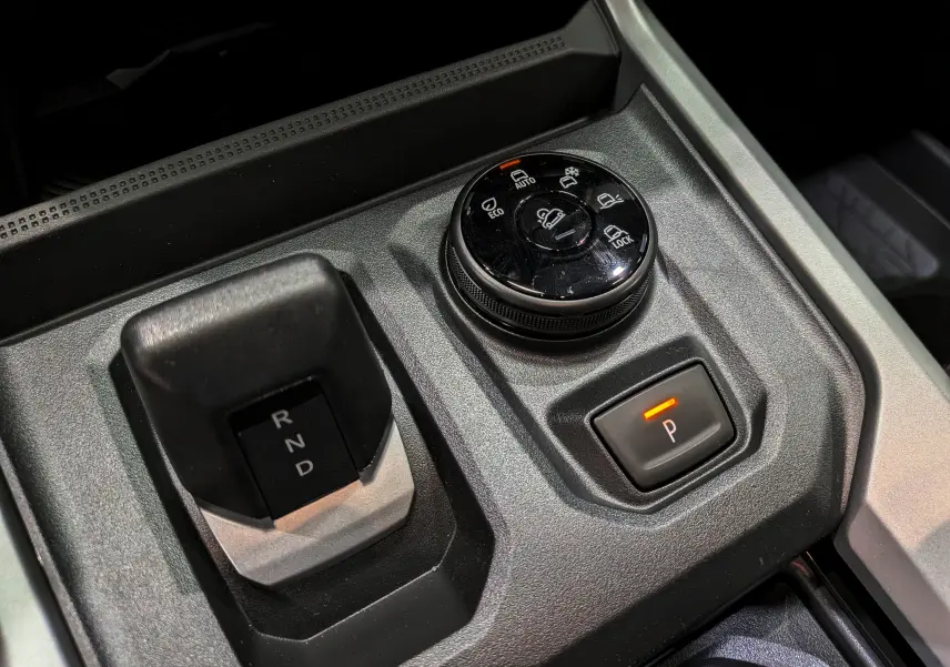 Gros plan sur la console centrale du Dacia Bigster Hybrid-G 150 4x4 avec sélecteur de boîte auto et bouton de mode de conduite.