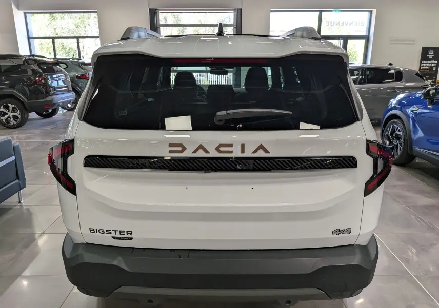 Vue arrière d’un Dacia Bigster blanc Glacier Hybrid-G 150 4x4, avec logo DACIA en relief et badges distinctifs visibles.