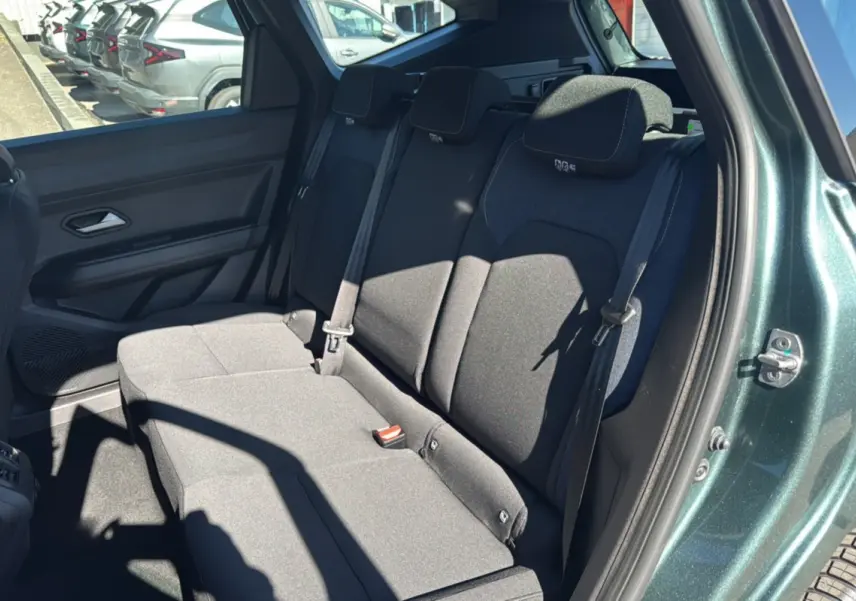 Vue intérieure côté droit sur la banquette arrière noire du Dacia Bigster vert cèdre avec porte ouverte.