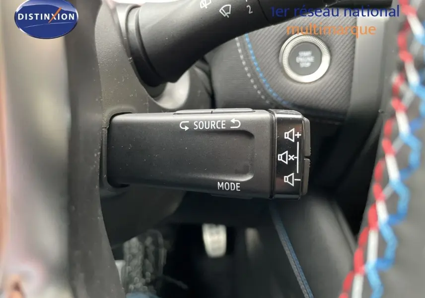 Gros plan sur la commande audio au volant du Renault Symbioz gris Rafale métal, avec bouton source et mode visibles.