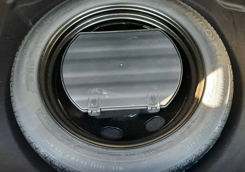Gros plan sur la roue de secours et son compartiment dans le coffre du Peugeot 3008 gris platinium 2023.