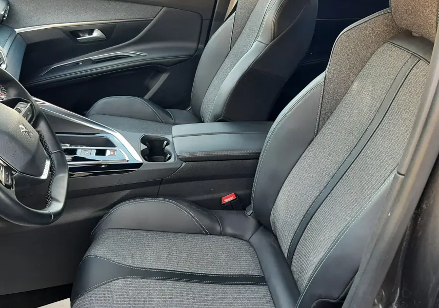 Vue intérieure côté conducteur du Peugeot 3008 2023, sièges tissu gris et cuir noir avec console centrale moderne.