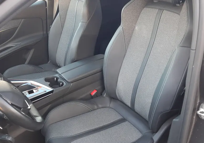 Vue intérieure côté conducteur du Peugeot 3008 2023, sièges tissu gris et cuir noir avec surpiqûres contrastantes.