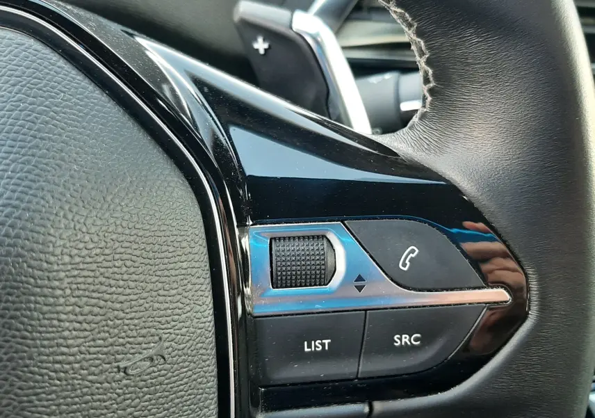 Gros plan sur les commandes à droite du volant noir du Peugeot 3008 gris platinium, avec molette et boutons d’appel.