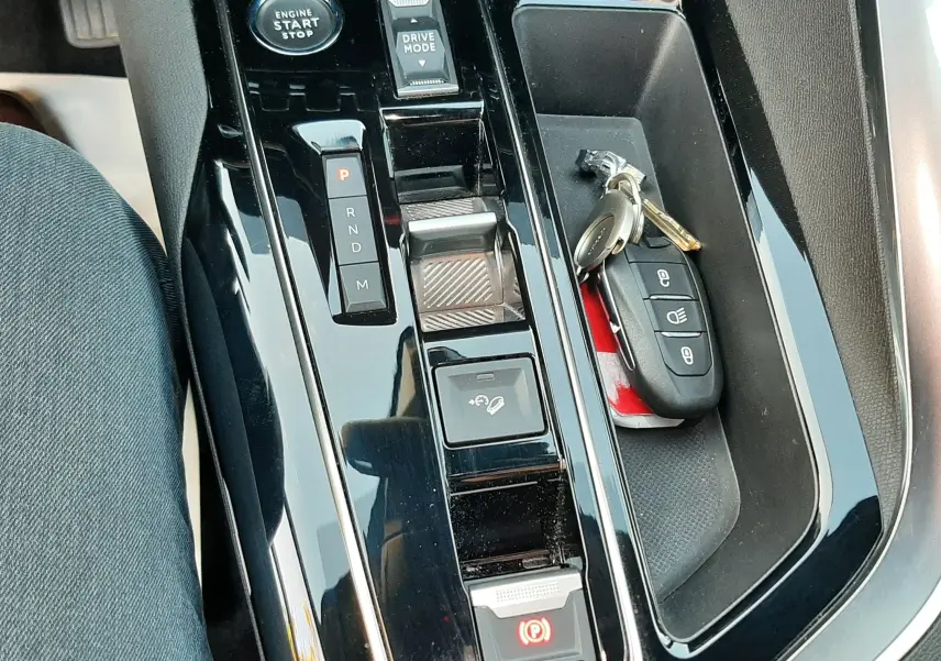 Vue rapprochée de la console centrale noire brillante du Peugeot 3008 2023 avec clés et sélecteur de boîte automatique.