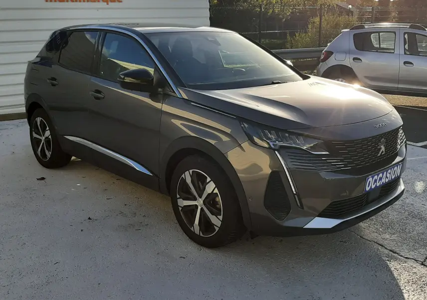 Peugeot 3008 gris platinium en 3/4 avant droit, avec jantes alliage et calandre distinctive, stationné en extérieur.