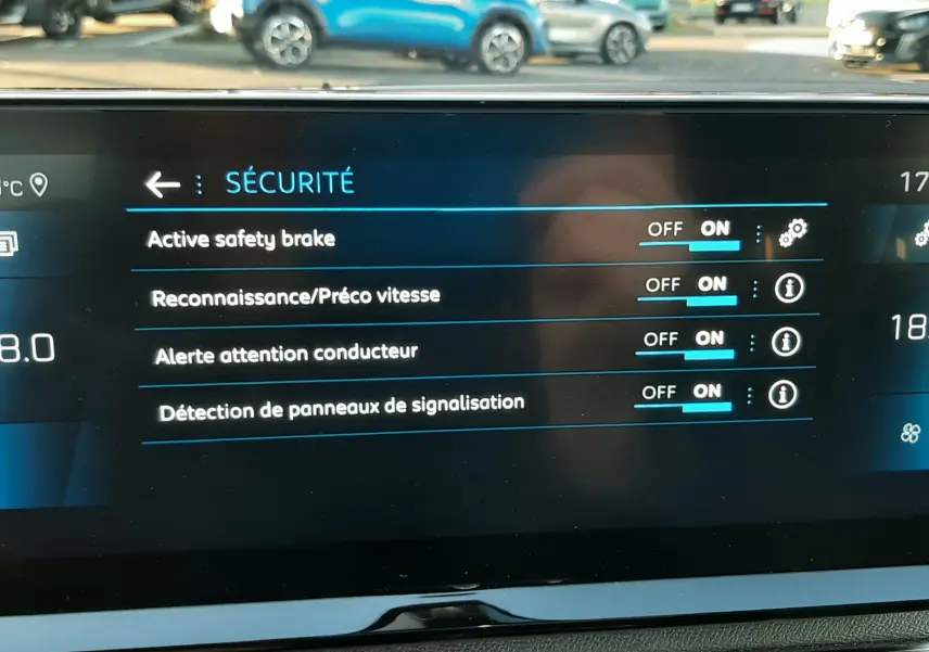 Écran tactile intérieur du Peugeot 3008 2023 montrant les réglages de sécurité activés, avec vue floue sur l'extérieur.