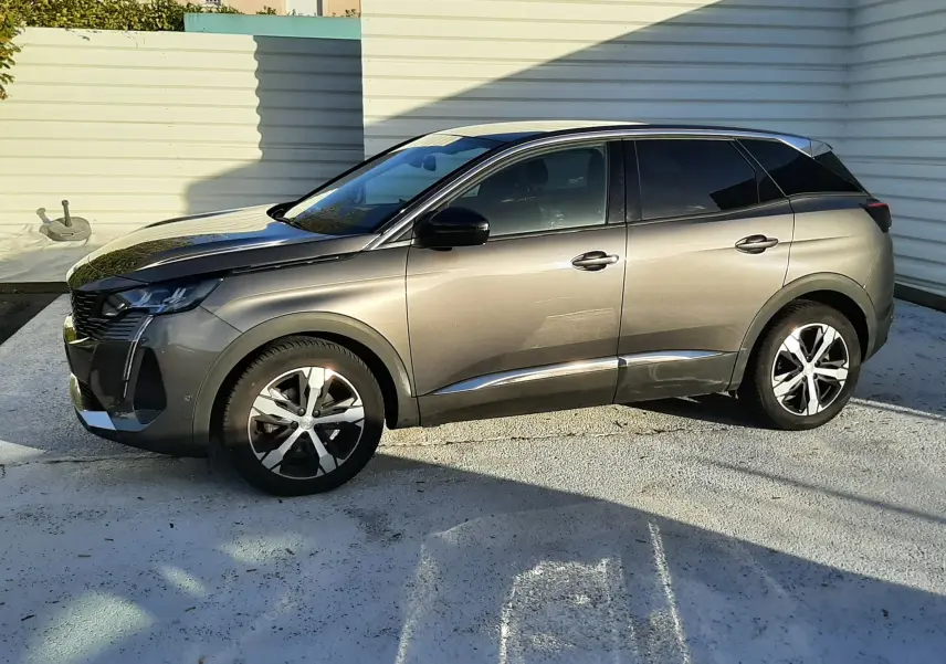 Peugeot 3008 gris platinium vu de profil côté gauche, avec jantes alliage et vitres teintées, stationné en extérieur.